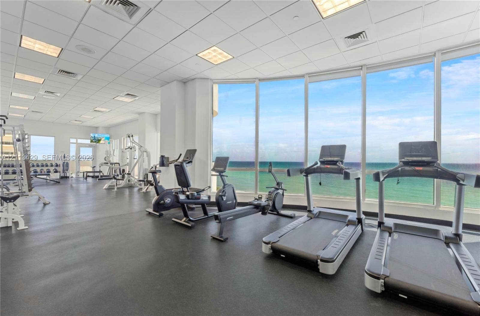 6365 Collins Avenue, #909, Miami Beach, FL 33141 Fitness center featuring floor-to-ceiling windows, panoramic ocean scenery, recessed ceiling lighting, and resilient rubber flooring