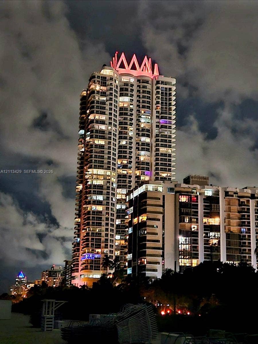 6365 Collins Avenue, #909, Miami Beach, FL 33141 High-rise architectural structure featuring a prominent crown roof design, stacked balconies, and expansive glass exterior glazing