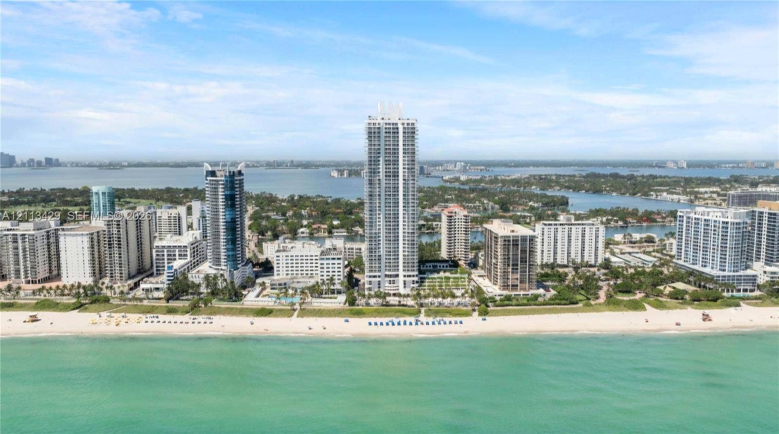 6365 Collins Avenue, #909, Miami Beach, FL 33141 Aerial perspective featuring a direct beachfront location, high-rise architectural structures, expansive coastal shoreline, and surrounding waterfront scenery