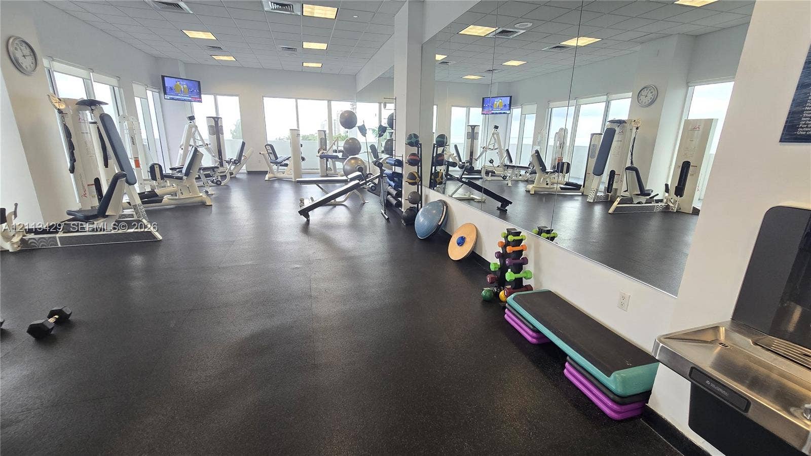6365 Collins Avenue, #909, Miami Beach, FL 33141 Fitness center featuring rubber flooring, floor-to-ceiling wall mirrors, recessed lighting, and a stainless steel wall-mounted water fountain