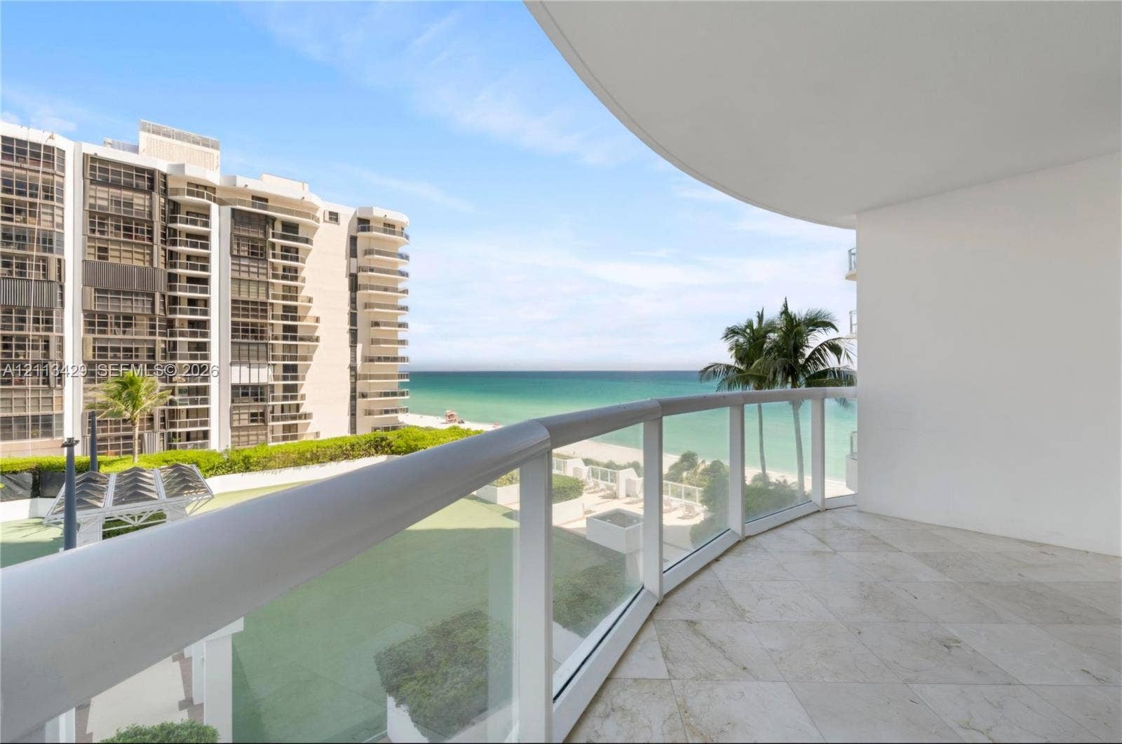 6365 Collins Avenue, #909, Miami Beach, FL 33141 Covered balcony featuring stone-tile flooring and a glass-paneled railing with a rounded metal top rail
