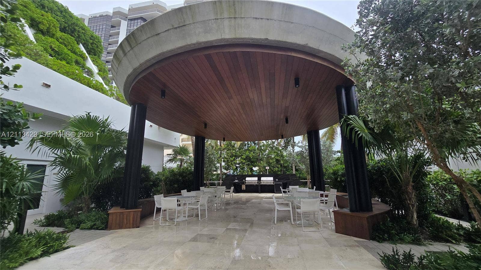 6365 Collins Avenue, #909, Miami Beach, FL 33141 Circular outdoor pavilion featuring a wood-plank ceiling, black cylindrical columns, stone-tile flooring, and a built-in outdoor kitchen station