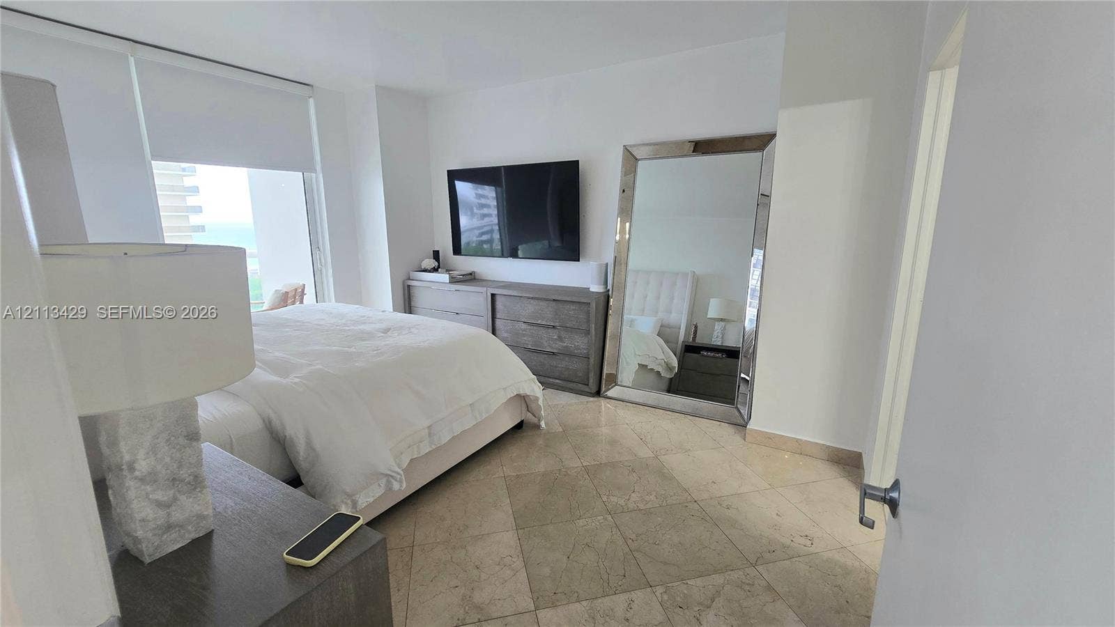 6365 Collins Avenue, #909, Miami Beach, FL 33141 Natural stone tile flooring, floor-to-ceiling window, and neutral wall palette