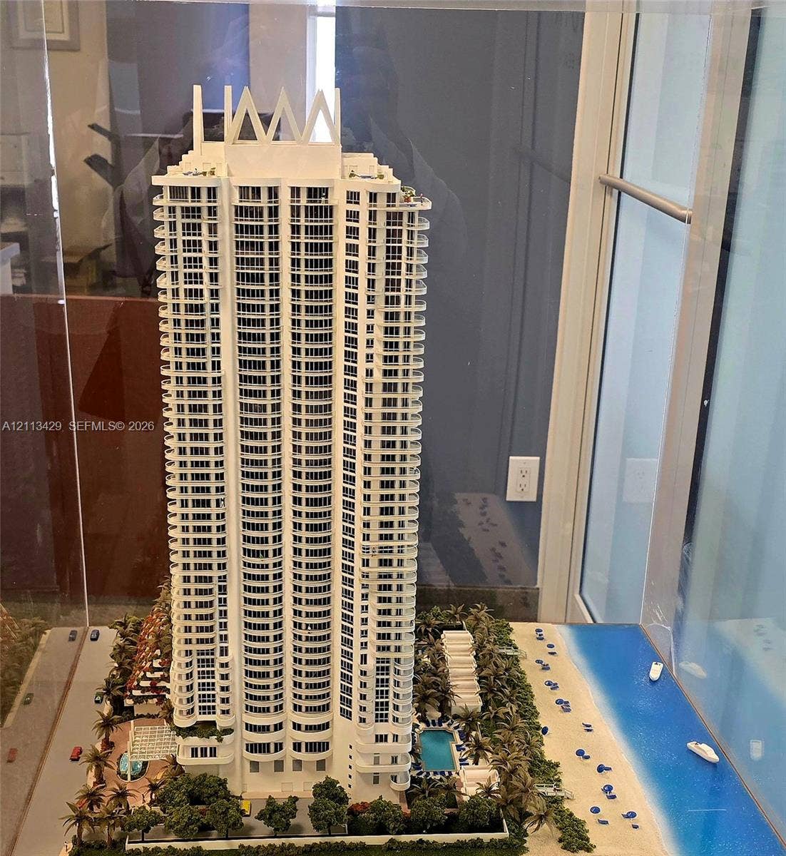 6365 Collins Avenue, #909, Miami Beach, FL 33141 High-rise architectural model featuring wraparound balconies, an outdoor swimming pool, landscaped grounds, and immediate beach access