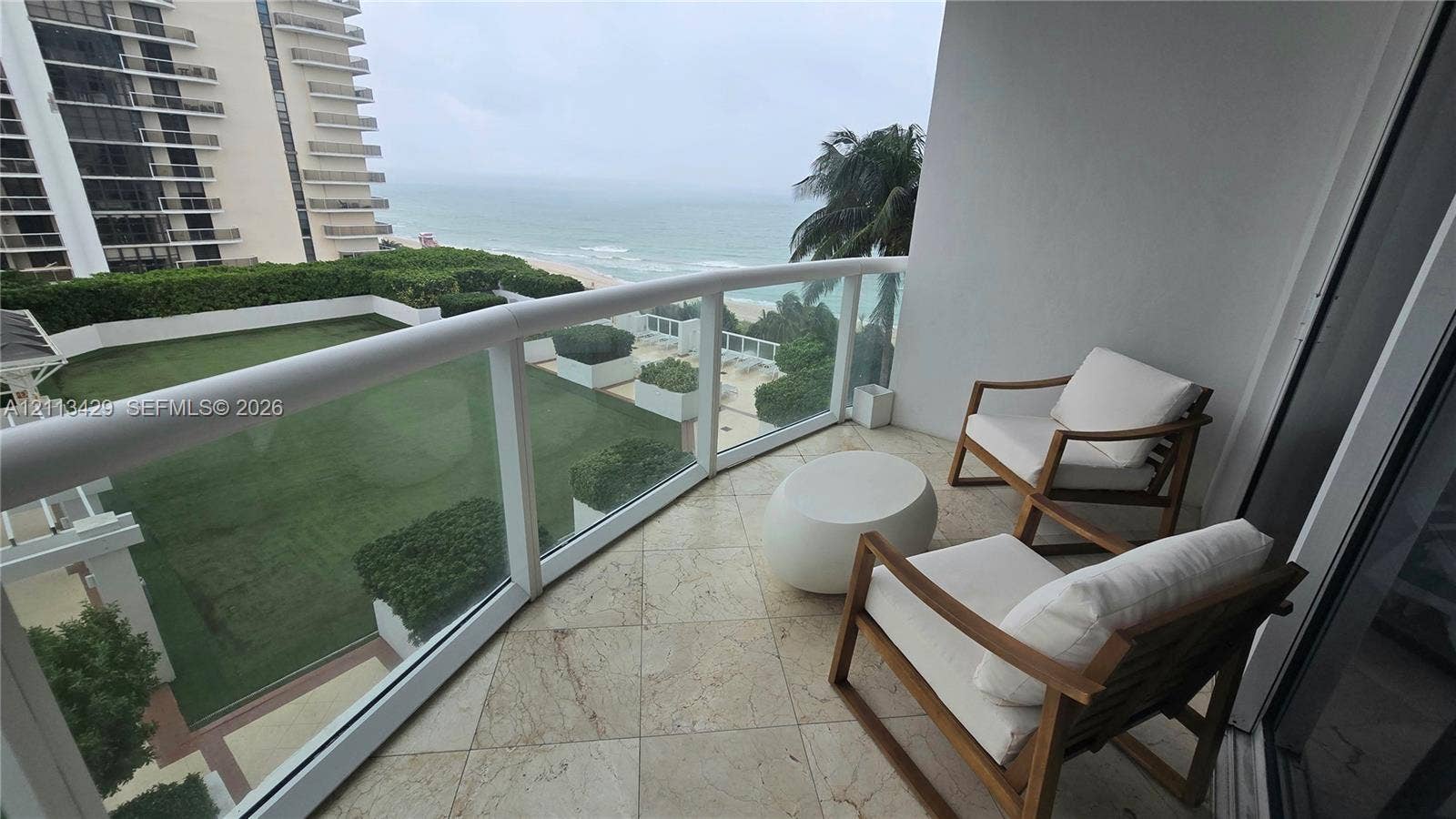 6365 Collins Avenue, #909, Miami Beach, FL 33141 Balcony featuring stone tile flooring, a glass and metal railing, and an expansive ocean backdrop