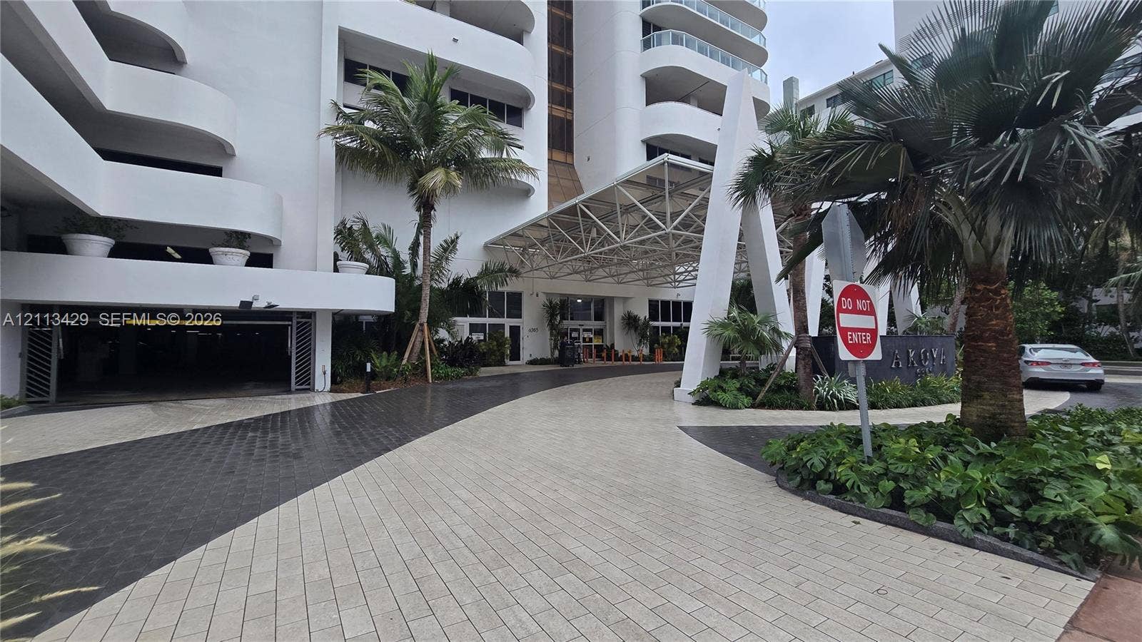 6365 Collins Avenue, #909, Miami Beach, FL 33141 Building exterior featuring a geometric porte-cochre, paved circular motor court, and covered parking entrance