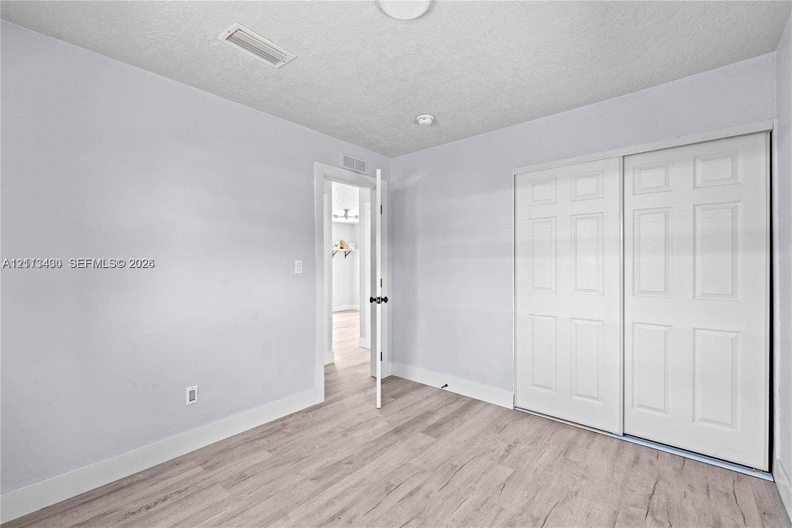5621 SW 38th Court, Davie, Davie, FL 33314 Neutral-toned room featuring wood-finish flooring, a double-panel sliding closet, and a white interior door with a matte black handle