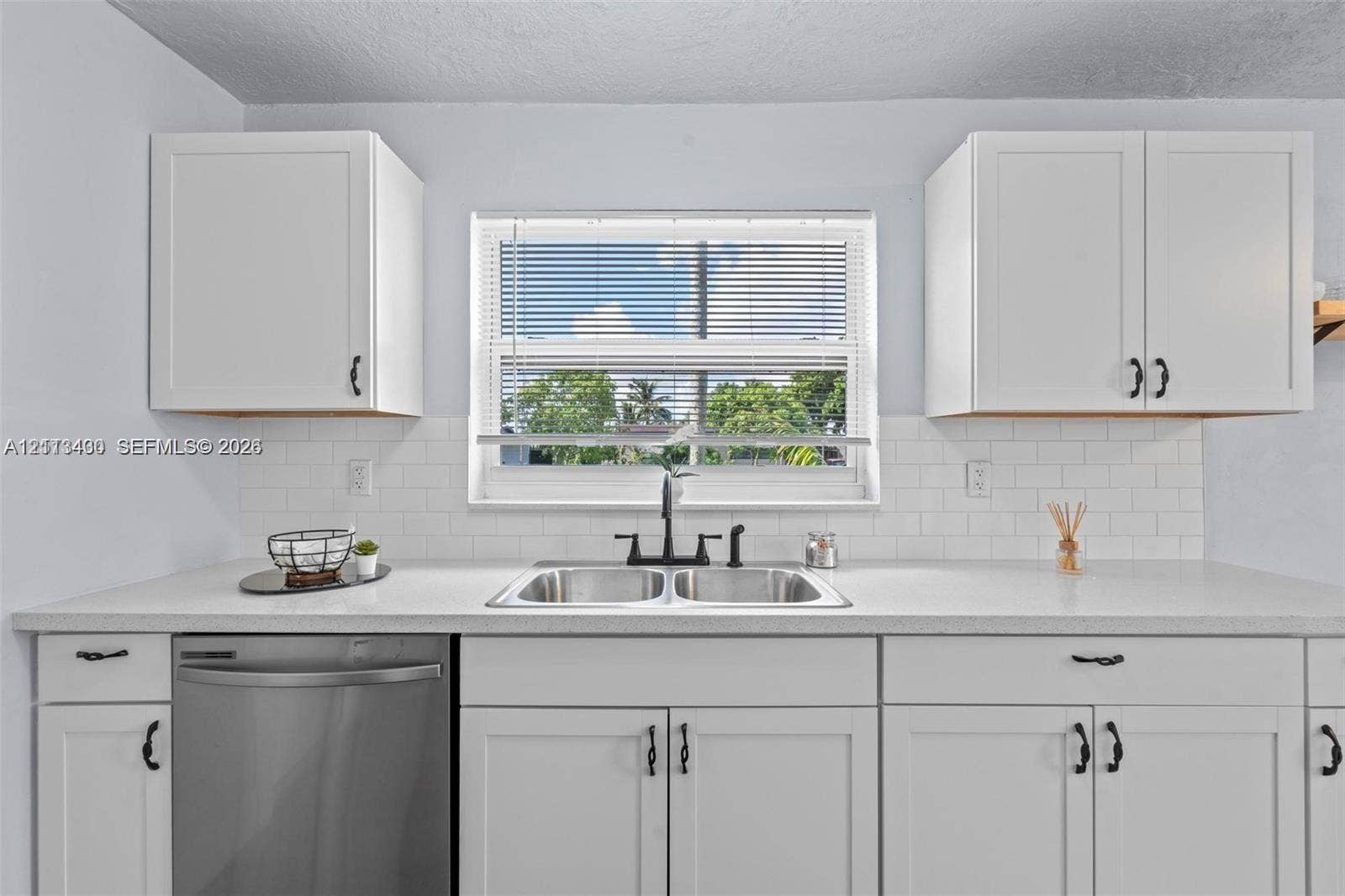 5621 SW 38th Court, Davie, Davie, FL 33314 White shaker-style cabinetry, stainless steel dishwasher, white subway tile backsplash, solid-surface countertop, and dual-basin stainless steel sink with matte black hardware
