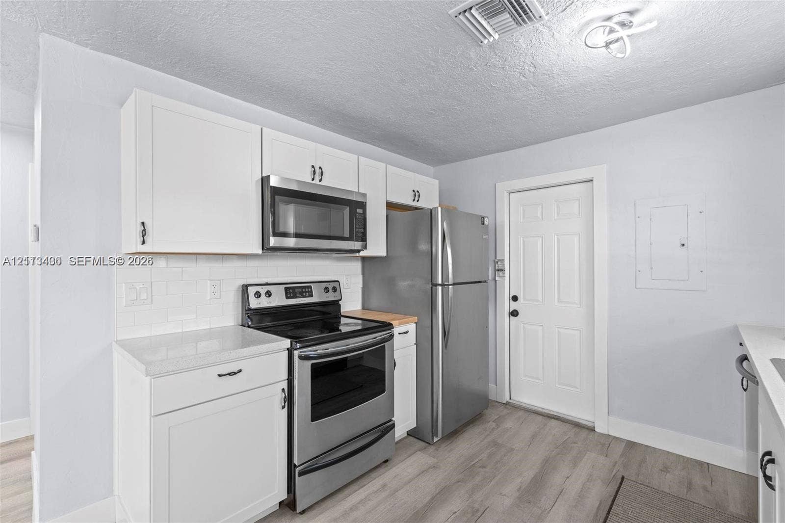 5621 SW 38th Court, Davie, Davie, FL 33314 Kitchen featuring white cabinetry, subway tile backsplash, wood-finish flooring, and stainless steel appliances