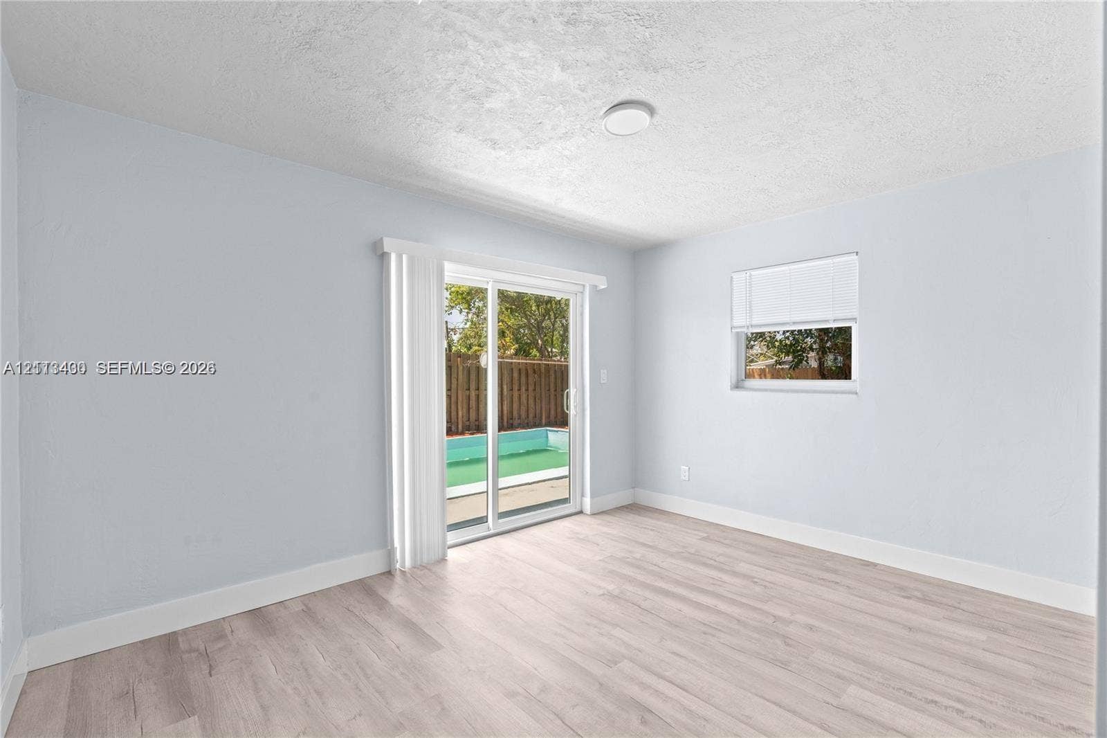 5621 SW 38th Court, Davie, Davie, FL 33314 Interior space featuring light wood-finish flooring, sliding glass patio doors, and a window with a fitted blind