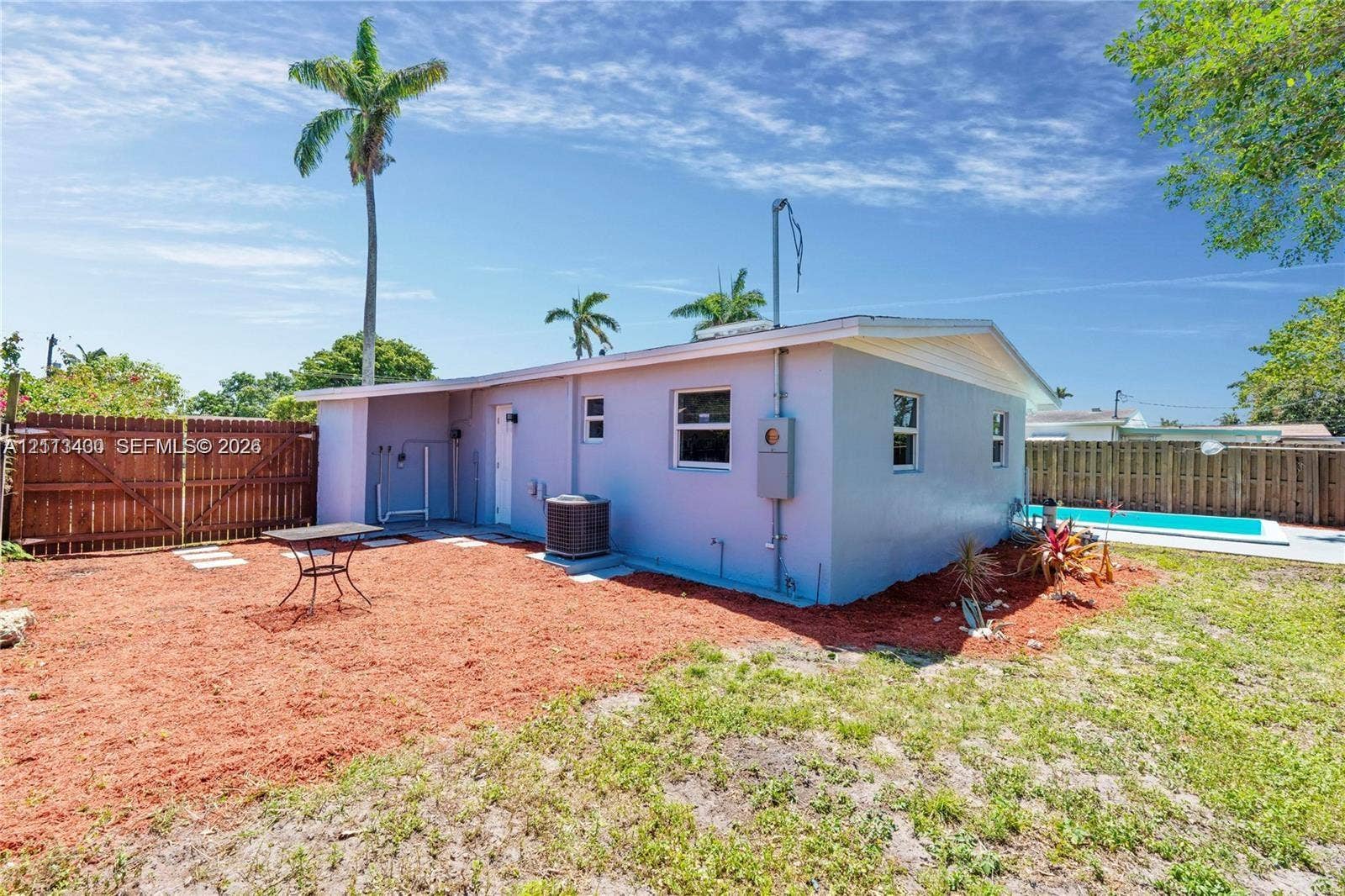 5621 SW 38th Court, Davie, Davie, FL 33314 Rear exterior featuring a stucco facade, wood-plank privacy fencing, and an in-ground swimming pool