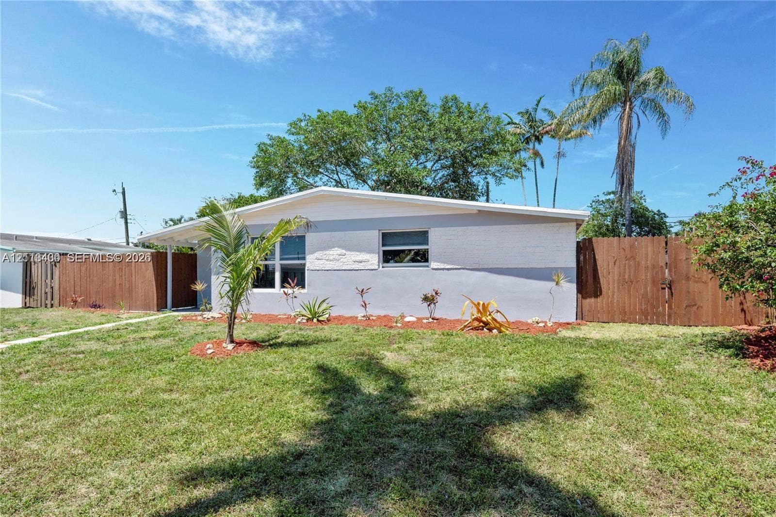 5621 SW 38th Court, Davie, Davie, FL 33314 Single-story exterior featuring a two-tone painted facade, horizontal sliding windows, a covered entryway, and wood-panel fencing