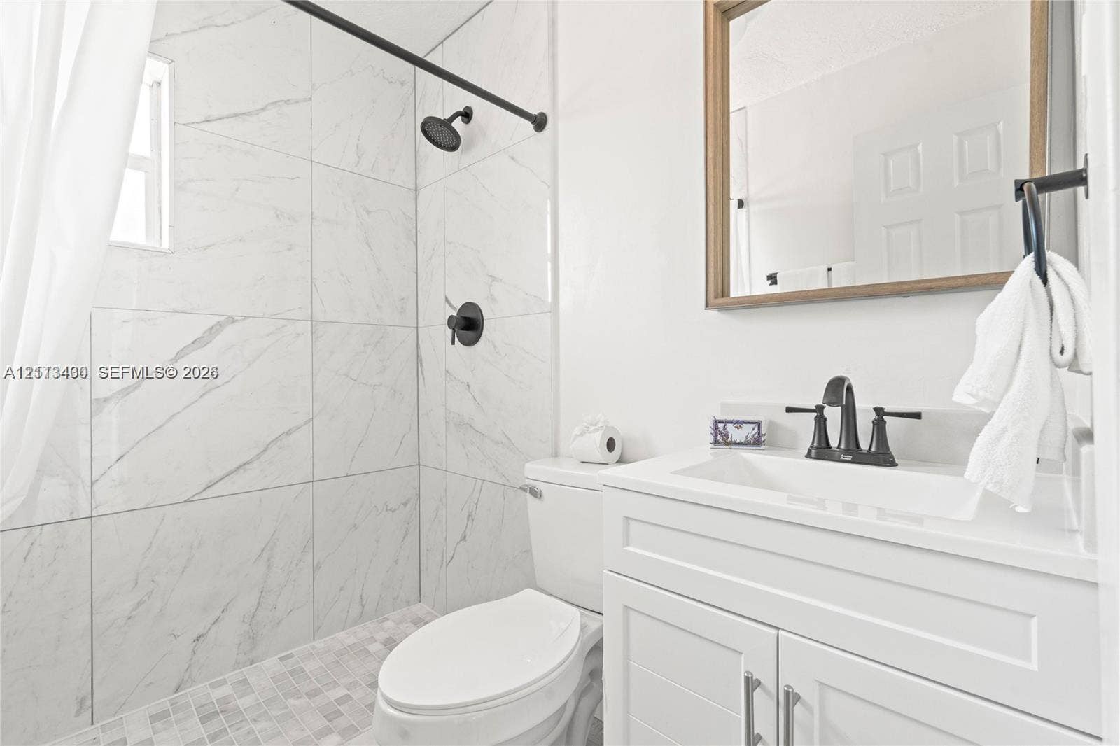 5621 SW 38th Court, Davie, Davie, FL 33314 Bathroom featuring floor-to-ceiling large-format tile shower surround, matte black rainfall shower head, white vanity cabinet with shaker-style doors, and rectangular undermount sink with widespread matte black faucet