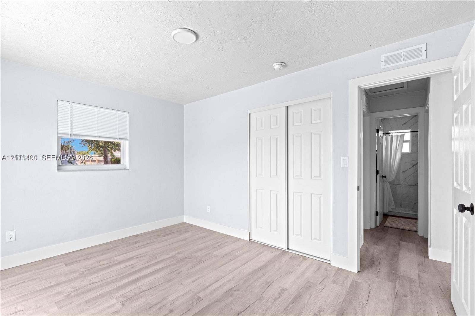 5621 SW 38th Court, Davie, Davie, FL 33314 Wood-finish flooring, white paneled closet doors, and window with horizontal blinds