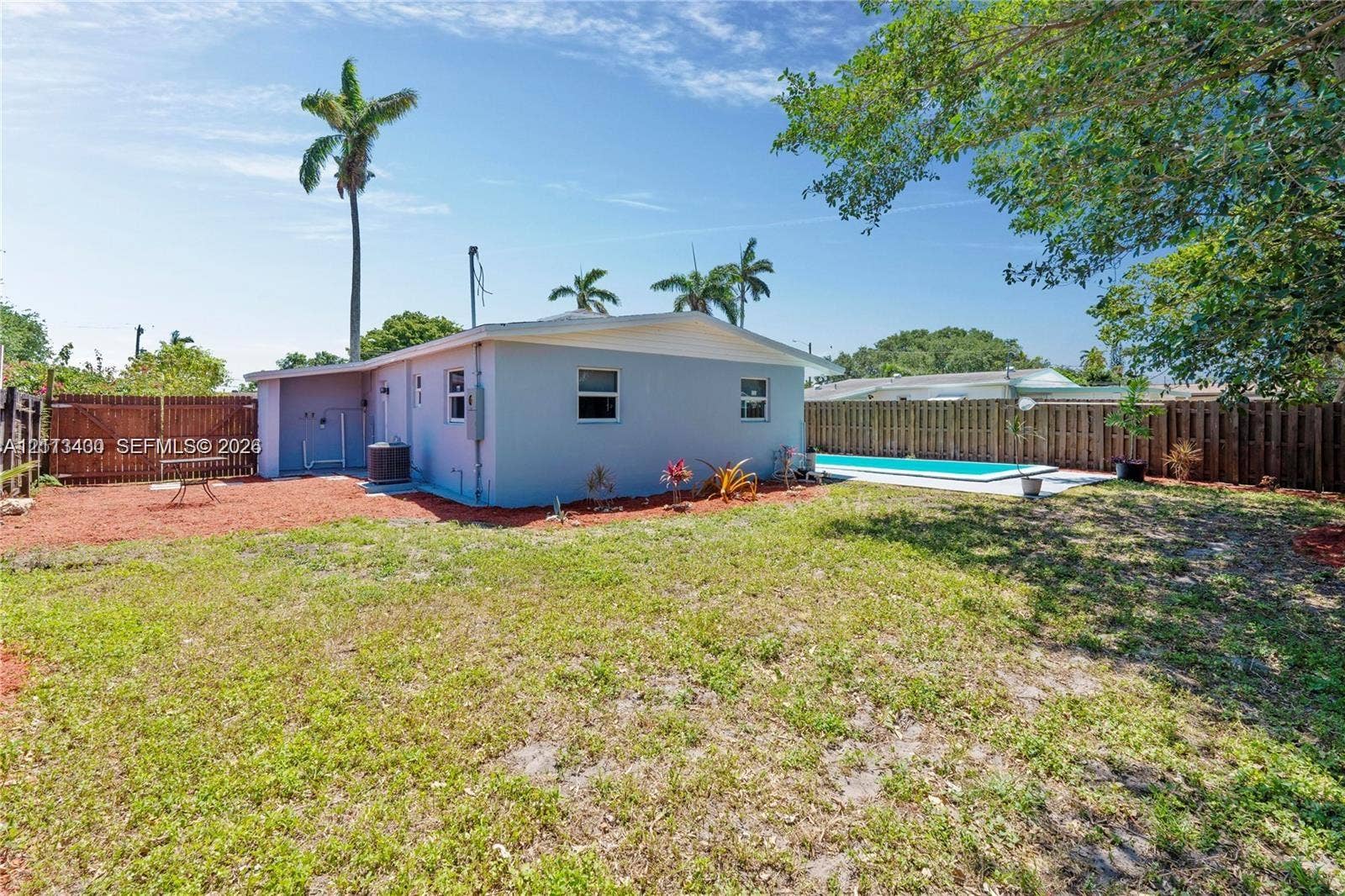 5621 SW 38th Court, Davie, Davie, FL 33314 Private backyard featuring an in-ground swimming pool, concrete pool deck, enclosed perimeter wood fencing, and mature palm trees