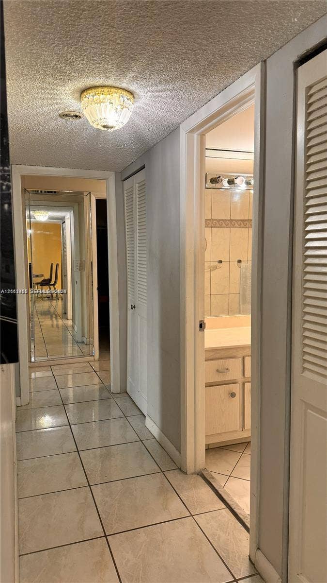 3800 S Ocean Drive, #416, Hollywood, FL 33019 Hallway featuring ceramic tile flooring, built-in louvered-door closets, and a decorative flush-mount ceiling light