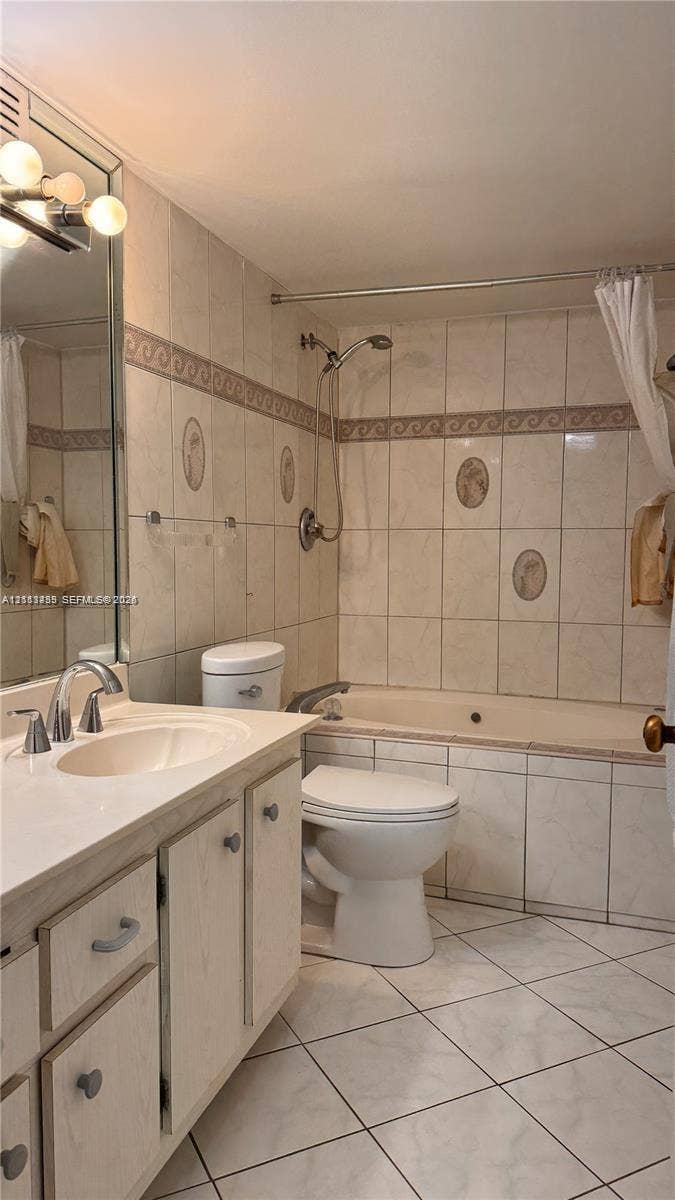 3800 S Ocean Drive, #416, Hollywood, FL 33019 Bathroom featuring a vanity with an integrated basin, a soaking tub with a wall-mounted handheld shower fixture, tiled surround with decorative accents, and tiled flooring
