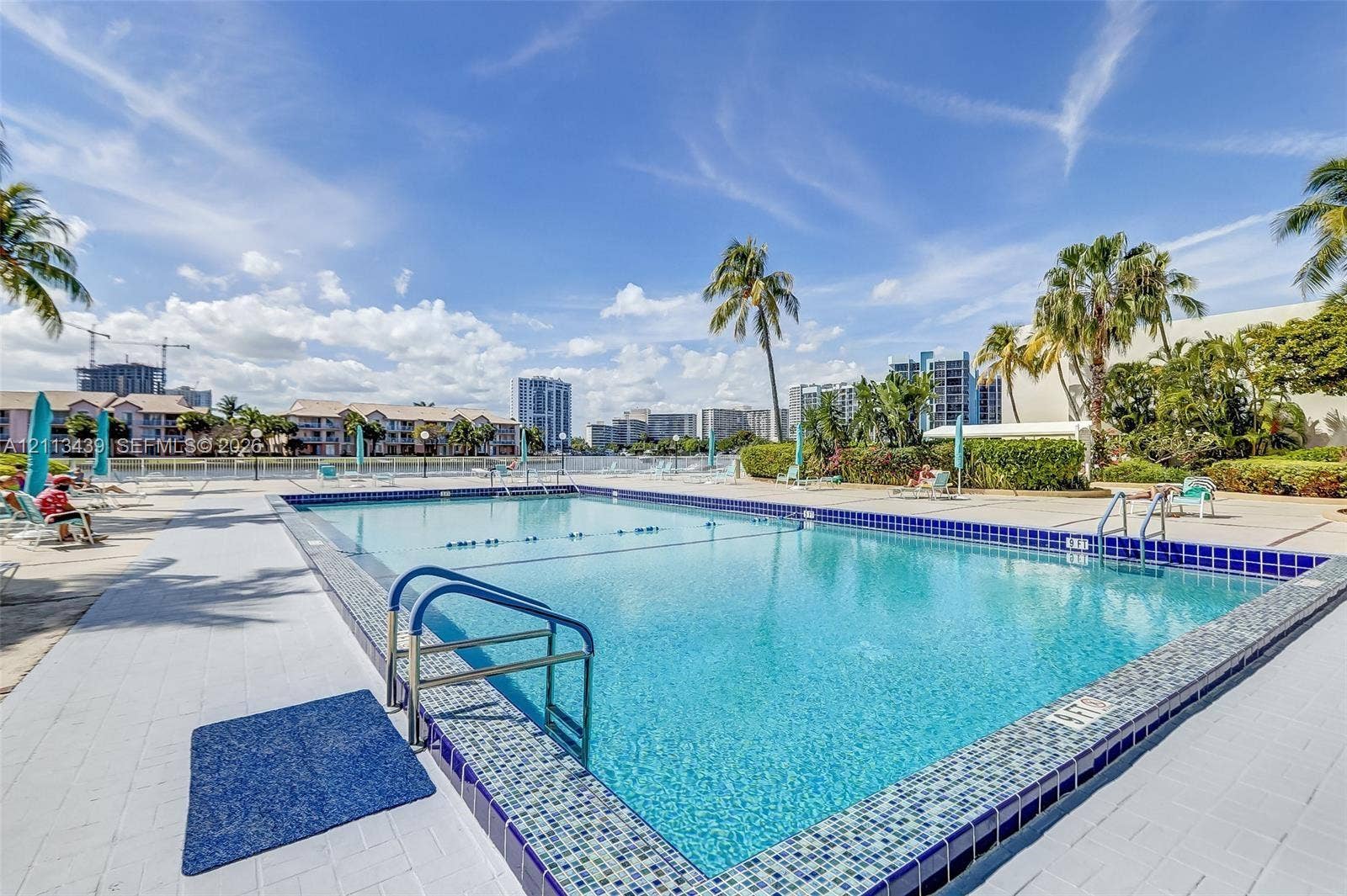 3800 S Ocean Drive, #416, Hollywood, FL 33019 Rectangular swimming pool featuring a decorative mosaic tile border, perimeter hardscaping, and integrated metal handrails