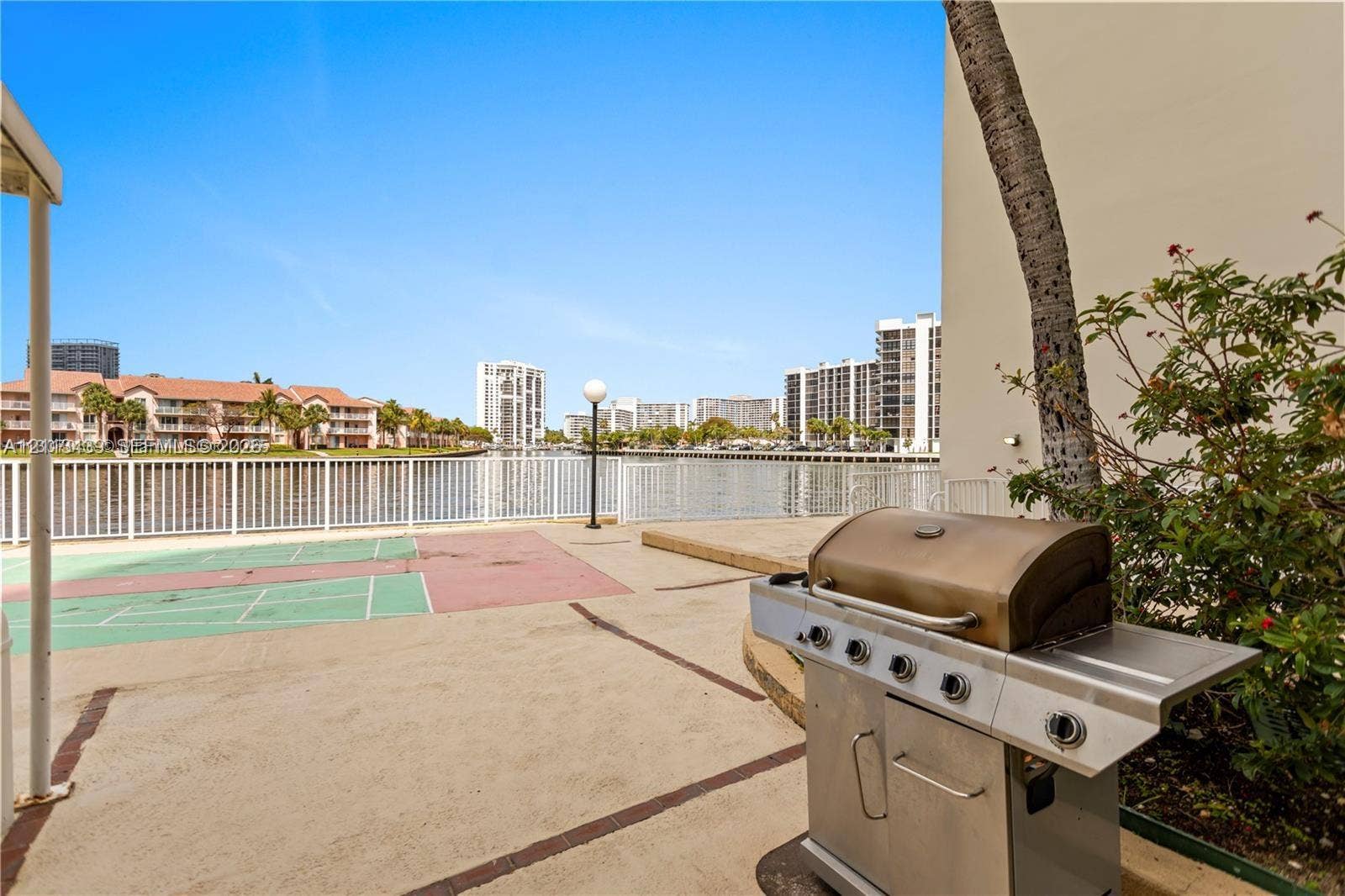 3800 S Ocean Drive, #416, Hollywood, FL 33019 Waterfront patio featuring a stainless steel grill, a concrete deck, a shuffleboard court, and a white metal safety railing