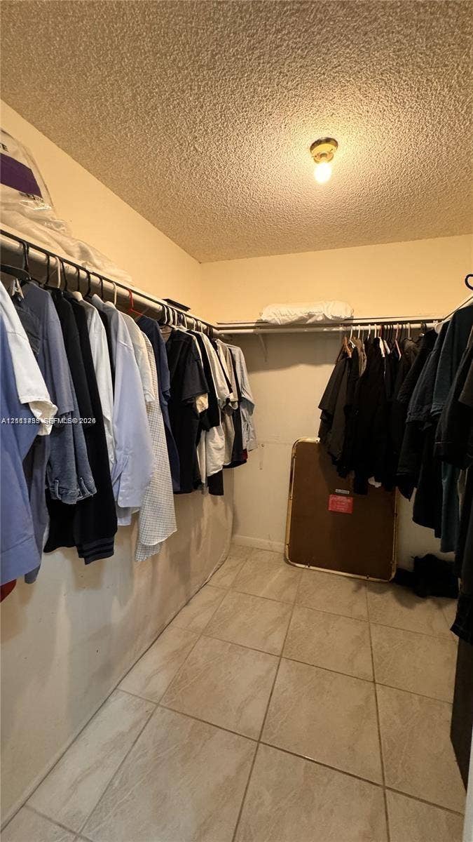 3800 S Ocean Drive, #416, Hollywood, FL 33019 Storage space featuring built-in shelving, hanging rods, and neutral-tone tile flooring