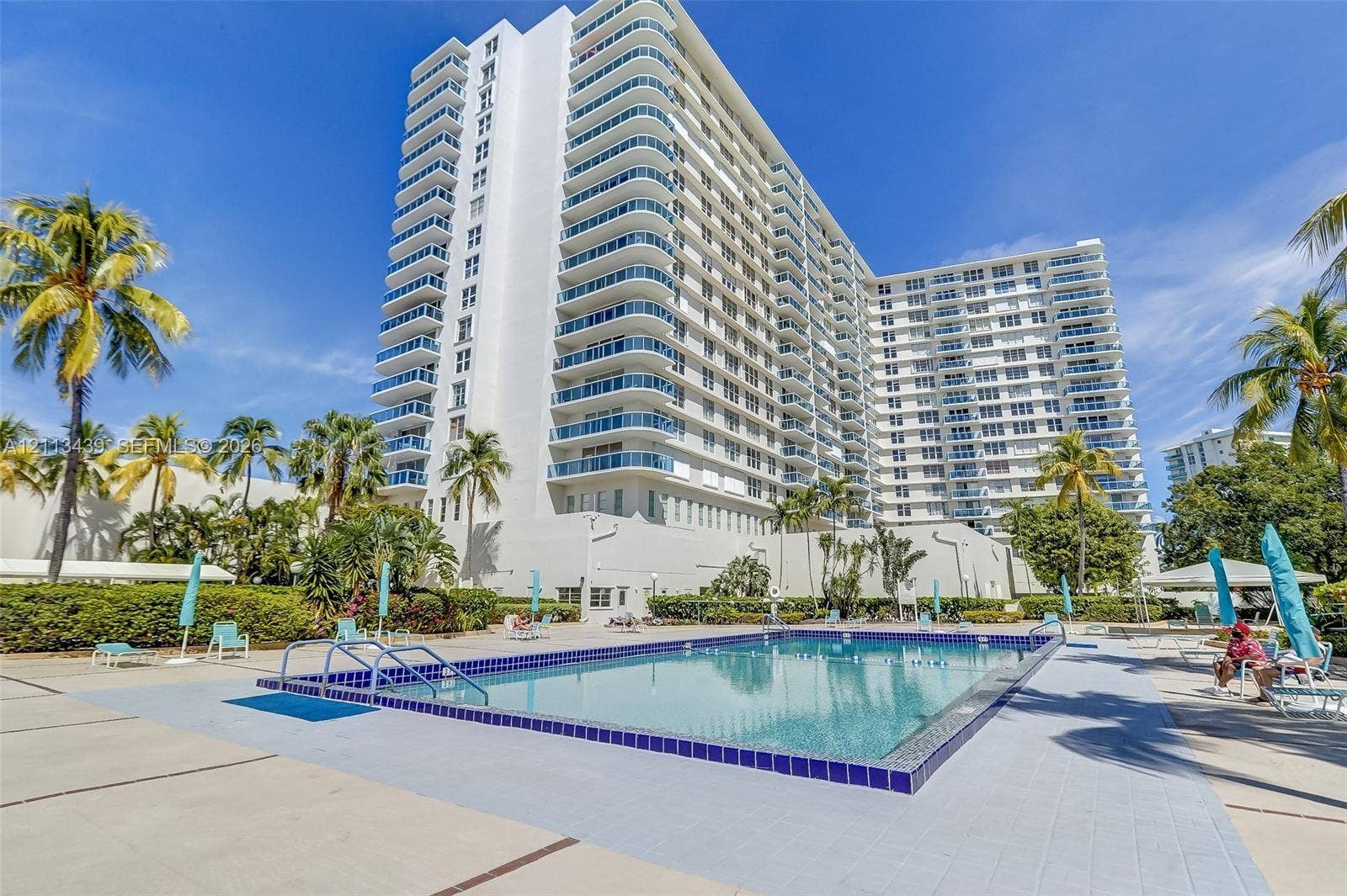 3800 S Ocean Drive, #416, Hollywood, FL 33019 High-rise residential exterior featuring private glass-railed balconies and a ground-level rectangular swimming pool with tile trim and concrete decking
