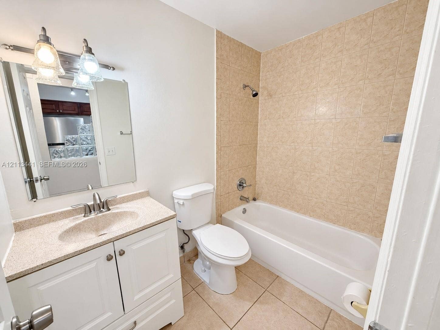 80 NE 36th Court, #82, Oakland Park, Oakland Park, FL 33334 Bathroom featuring white vanity cabinetry with a solid surface countertop, integrated sink, tile-surround shower-tub combination, and neutral-tone tile flooring