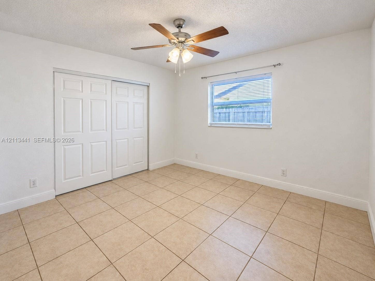 80 NE 36th Court, #82, Oakland Park, Oakland Park, FL 33334 Tile flooring, dual-panel sliding closet doors, ceiling fan with integrated lighting, and window with installed curtain rod