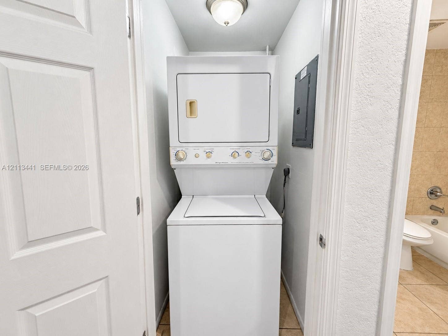 80 NE 36th Court, #82, Oakland Park, Oakland Park, FL 33334 Stackable laundry center featuring a top-loading washer and front-loading dryer, flush-mount ceiling light fixture, and tile flooring