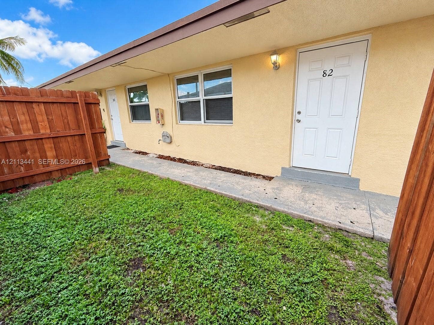 80 NE 36th Court, #82, Oakland Park, Oakland Park, FL 33334 Stucco exterior featuring dual-pane windows, wood-style privacy fencing, and a concrete walkway