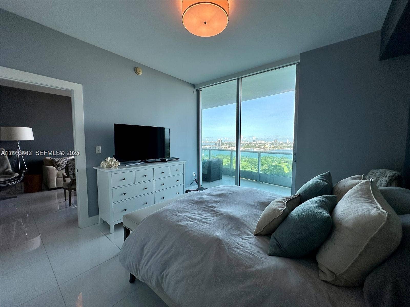 900 Biscayne Boulevard, #1903, Miami, Miami, FL 33132 Floor-to-ceiling glass sliding doors, private balcony, neutral large-format tile flooring, and a circular flush-mount ceiling light fixture