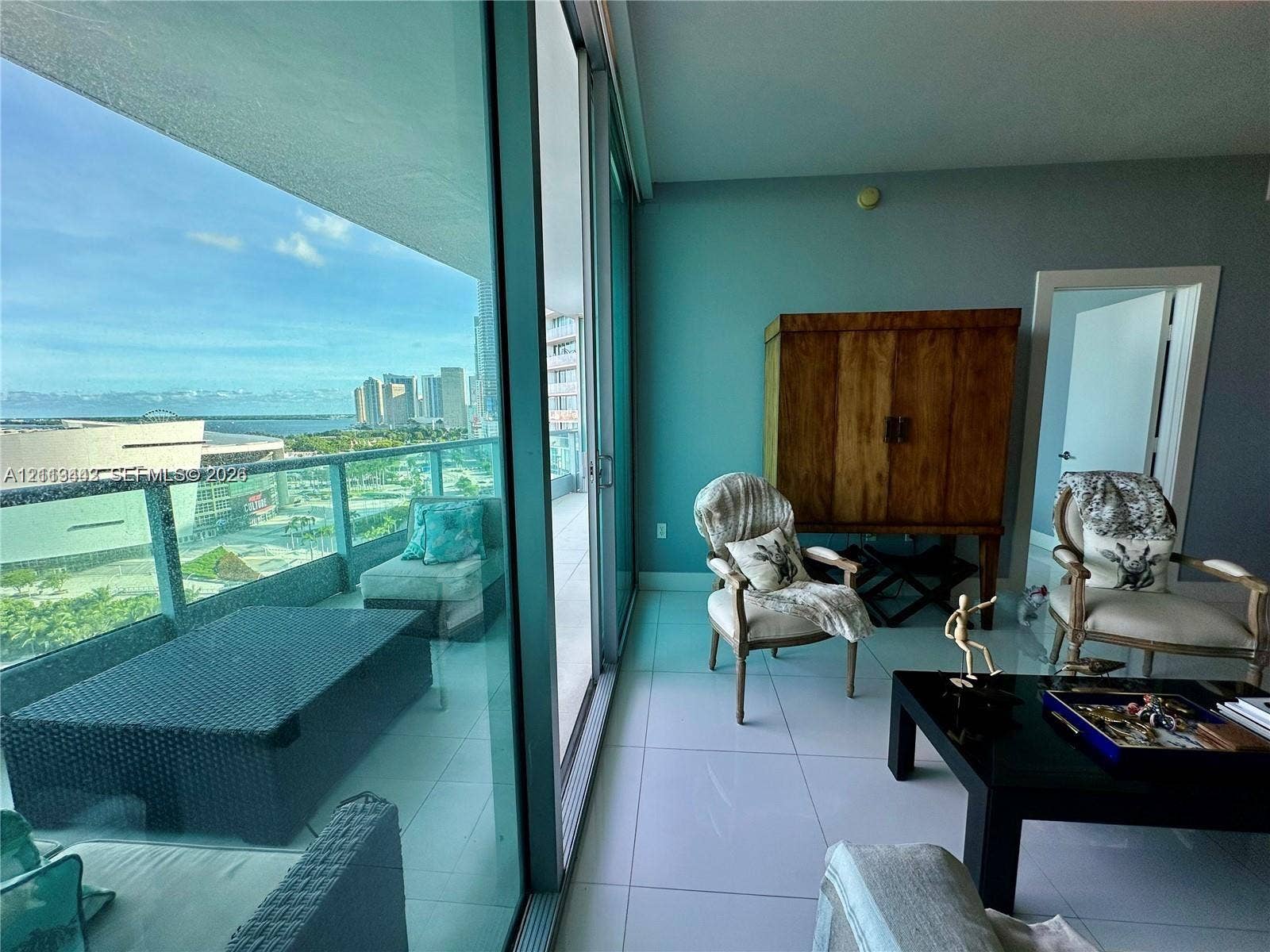 900 Biscayne Boulevard, #1903, Miami, Miami, FL 33132 Floor-to-ceiling glass sliding doors opening to an expansive balcony with glass railings, large-format tile flooring, and coastal skyline scenery