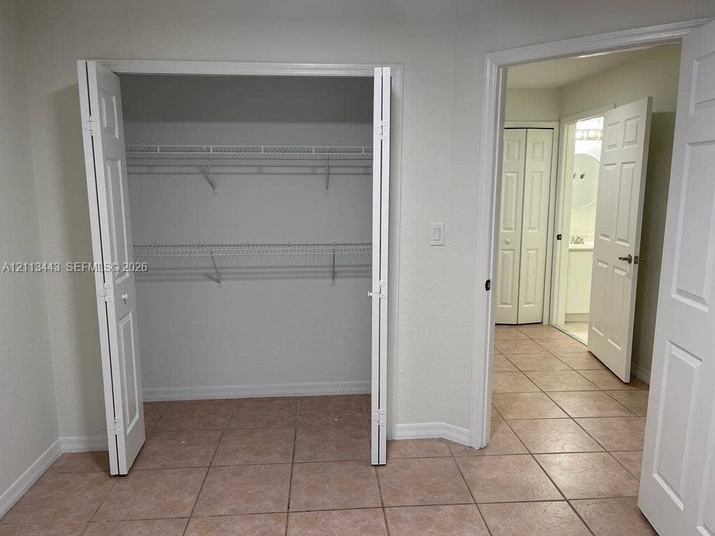 5705 NW 109th Avenue, #47, Doral, Doral, FL 33178 Closet featuring bi-fold doors and dual-tier wire shelving, finished with ceramic tile flooring