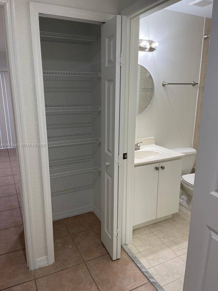 5705 NW 109th Avenue, #47, Doral, Doral, FL 33178 Built-in closet featuring white wire shelving, vanity with integrated basin, polished metal hardware, and ceramic tile flooring