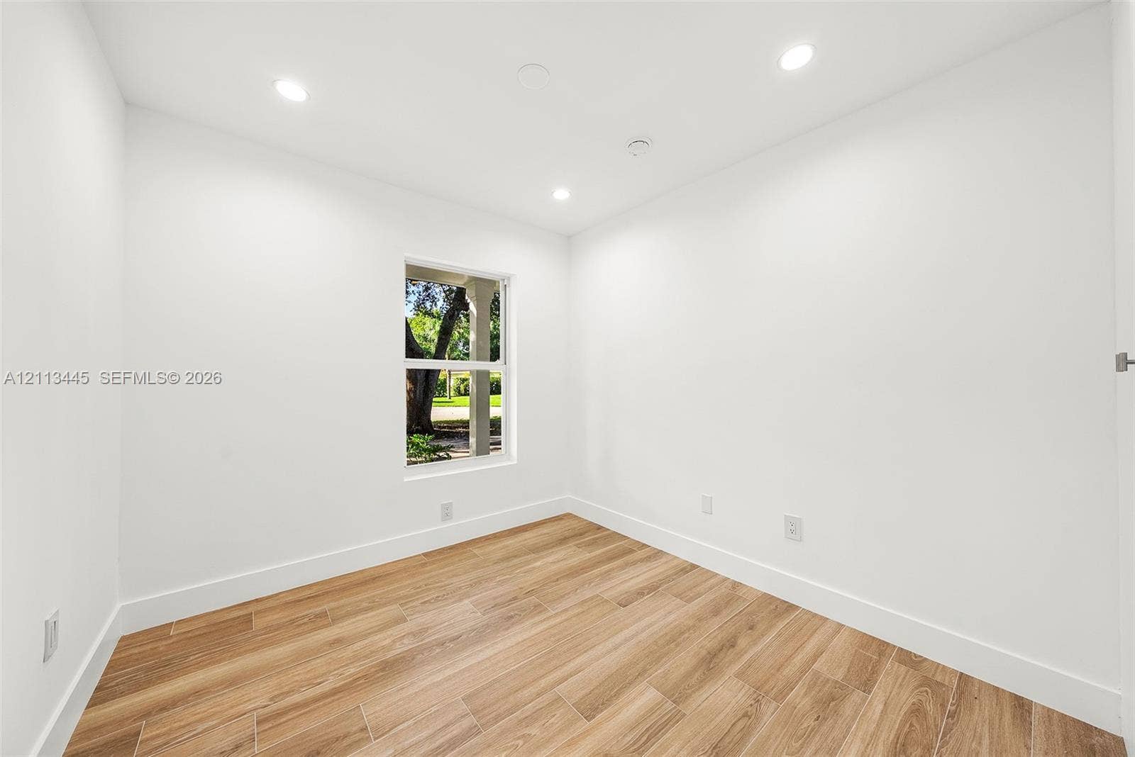 6951 SW 134th Street, Pinecrest, Pinecrest, FL 33156 Room featuring wood-finish flooring, recessed lighting, and a single window with exterior greenery