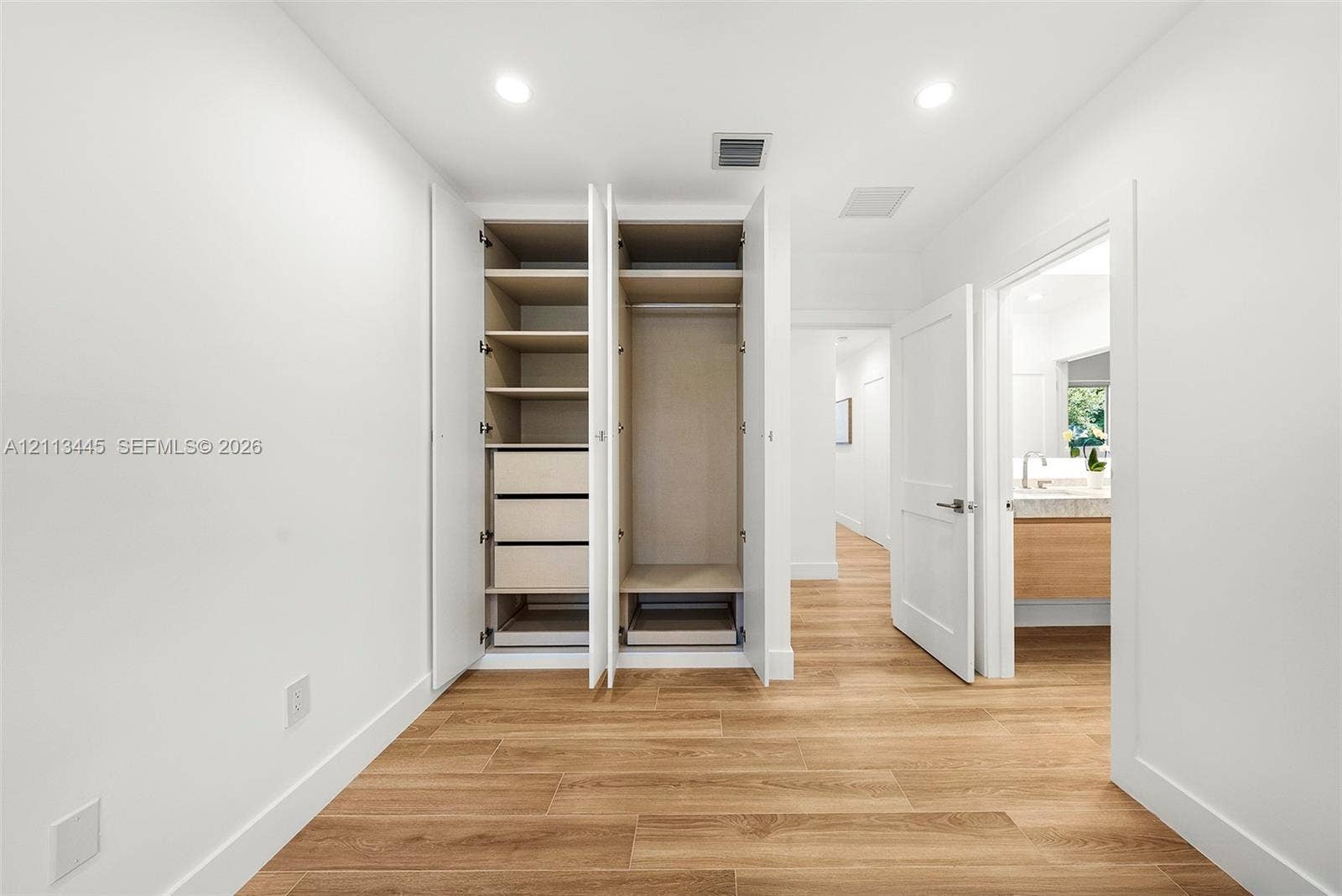 6951 SW 134th Street, Pinecrest, Pinecrest, FL 33156 Built-in cabinetry featuring adjustable shelving and integrated drawer storage, recessed lighting, and wood-finish flooring