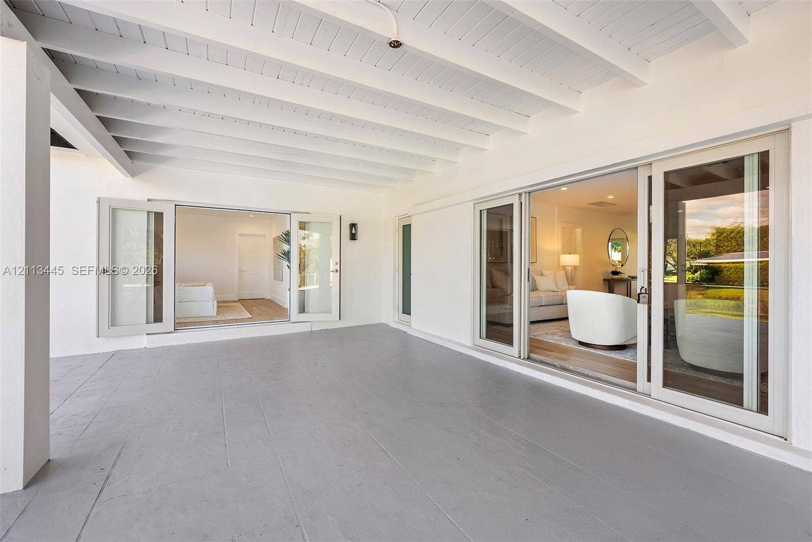 6951 SW 134th Street, Pinecrest, Pinecrest, FL 33156 Covered patio featuring an exposed-beam ceiling, solid-surface flooring, and glass-paneled doors