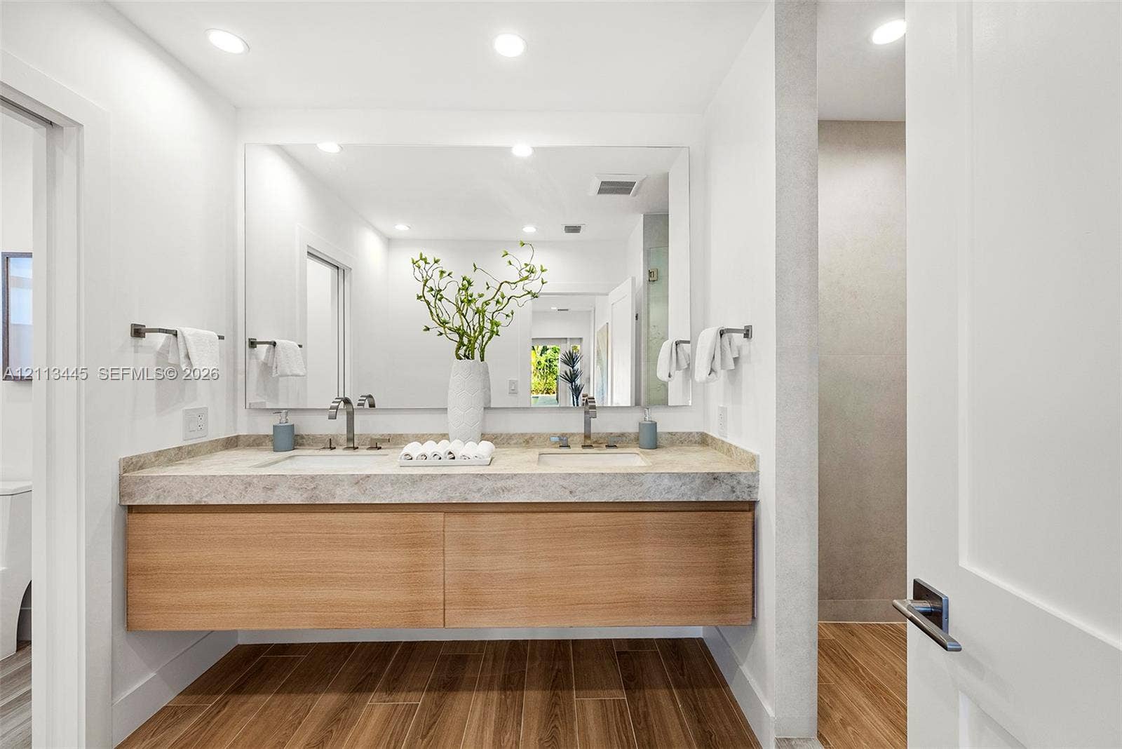 6951 SW 134th Street, Pinecrest, Pinecrest, FL 33156 Floating vanity featuring wood-finish cabinetry, dual undermount sinks, stone countertop, and full-width wall mirror