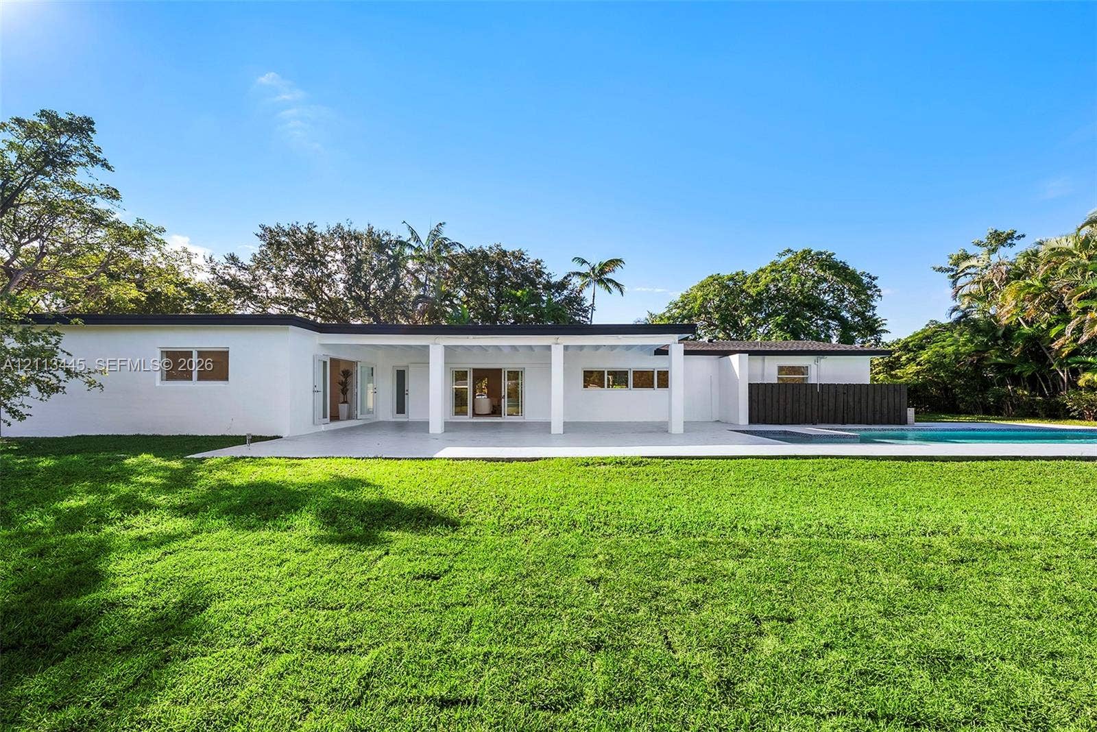 6951 SW 134th Street, Pinecrest, Pinecrest, FL 33156 Mid-century modern architectural style featuring an expansive covered patio, white exterior finish, flat roofline, and swimming pool