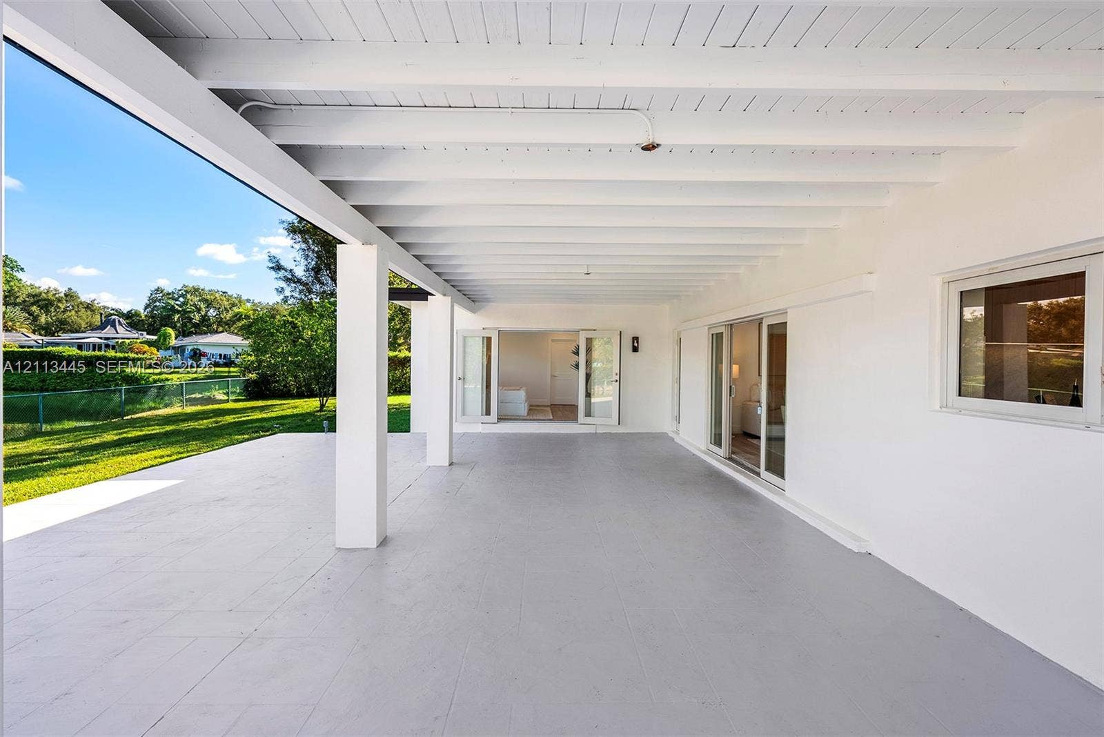 6951 SW 134th Street, Pinecrest, Pinecrest, FL 33156 Covered patio featuring a painted wood-beam ceiling, concrete flooring, sliding glass doors, and French doors