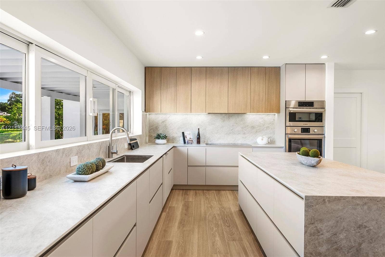 6951 SW 134th Street, Pinecrest, Pinecrest, FL 33156 Kitchen featuring flat-panel cabinetry in matte and light wood finishes, stone-composite countertops, built-in stainless steel double ovens, and wood-finish flooring
