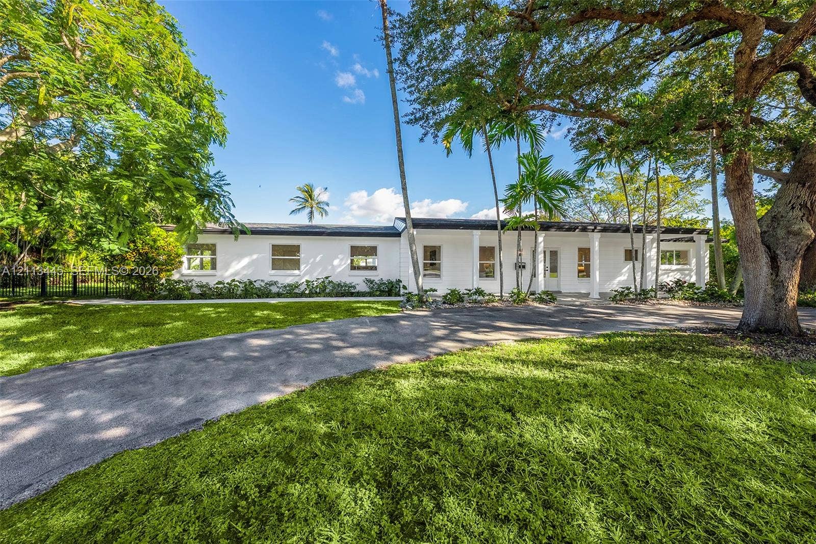 6951 SW 134th Street, Pinecrest, Pinecrest, FL 33156 Single-story exterior featuring a covered front porch with white columns, paved driveway, and mature landscaping