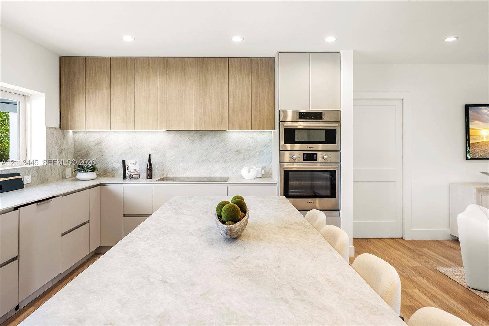 6951 SW 134th Street, Pinecrest, Pinecrest, FL 33156 Kitchen featuring wood-finish upper cabinetry, light-toned stone-style countertops and backsplash, integrated stainless steel double wall oven, and a central island