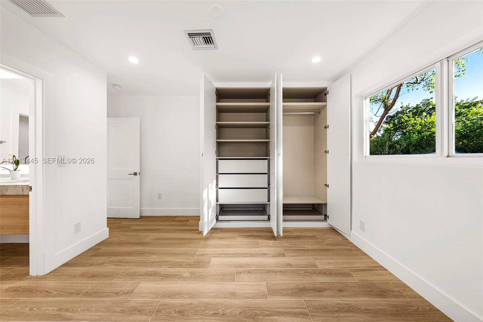 6951 SW 134th Street, Pinecrest, Pinecrest, FL 33156 Built-in wardrobe featuring integrated shelving, pull-out drawers, and hanging rods, complemented by wood-finish flooring and recessed lighting