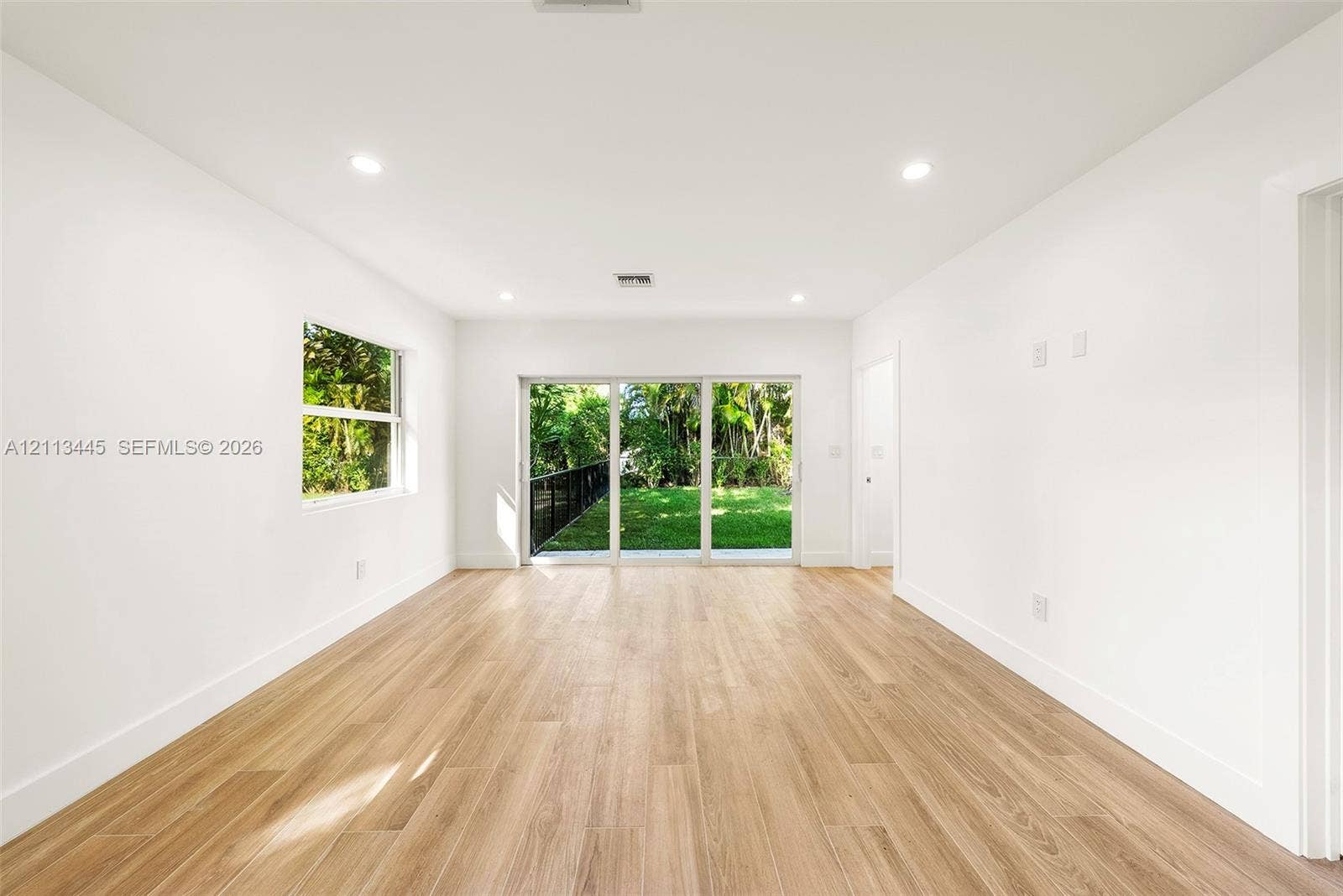6951 SW 134th Street, Pinecrest, Pinecrest, FL 33156 Interior space featuring wood-finish flooring, recessed lighting, a single-pane window, and large sliding glass doors providing access to the exterior