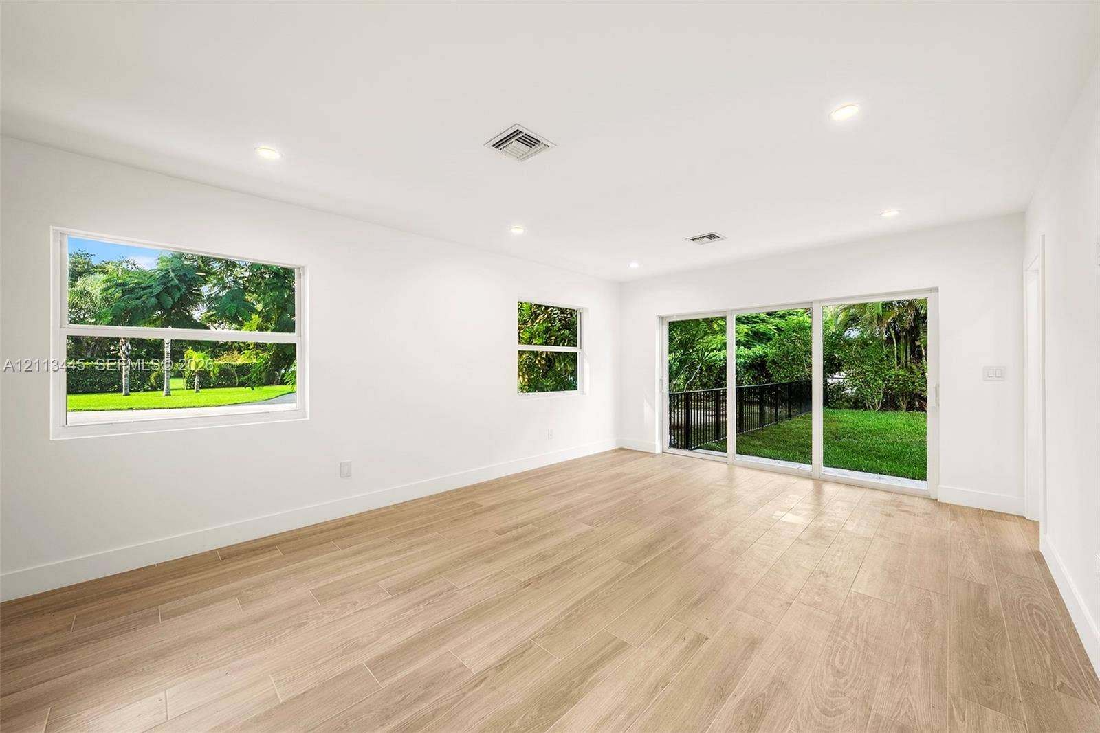 6951 SW 134th Street, Pinecrest, Pinecrest, FL 33156 Neutral interior space featuring wood-finish flooring, recessed lighting, and large windows