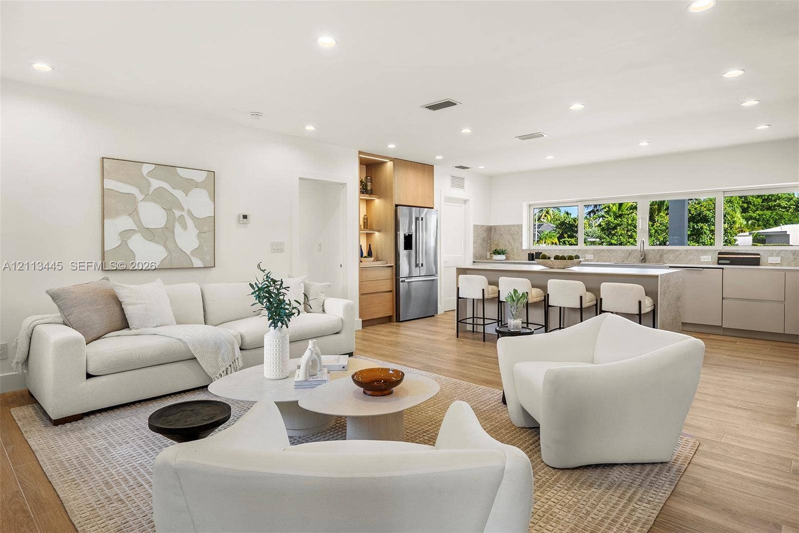 6951 SW 134th Street, Pinecrest, Pinecrest, FL 33156 Open-concept kitchen featuring an expansive center island, integrated cabinetry, stainless steel appliances, and wood-finish flooring illuminated by recessed lighting