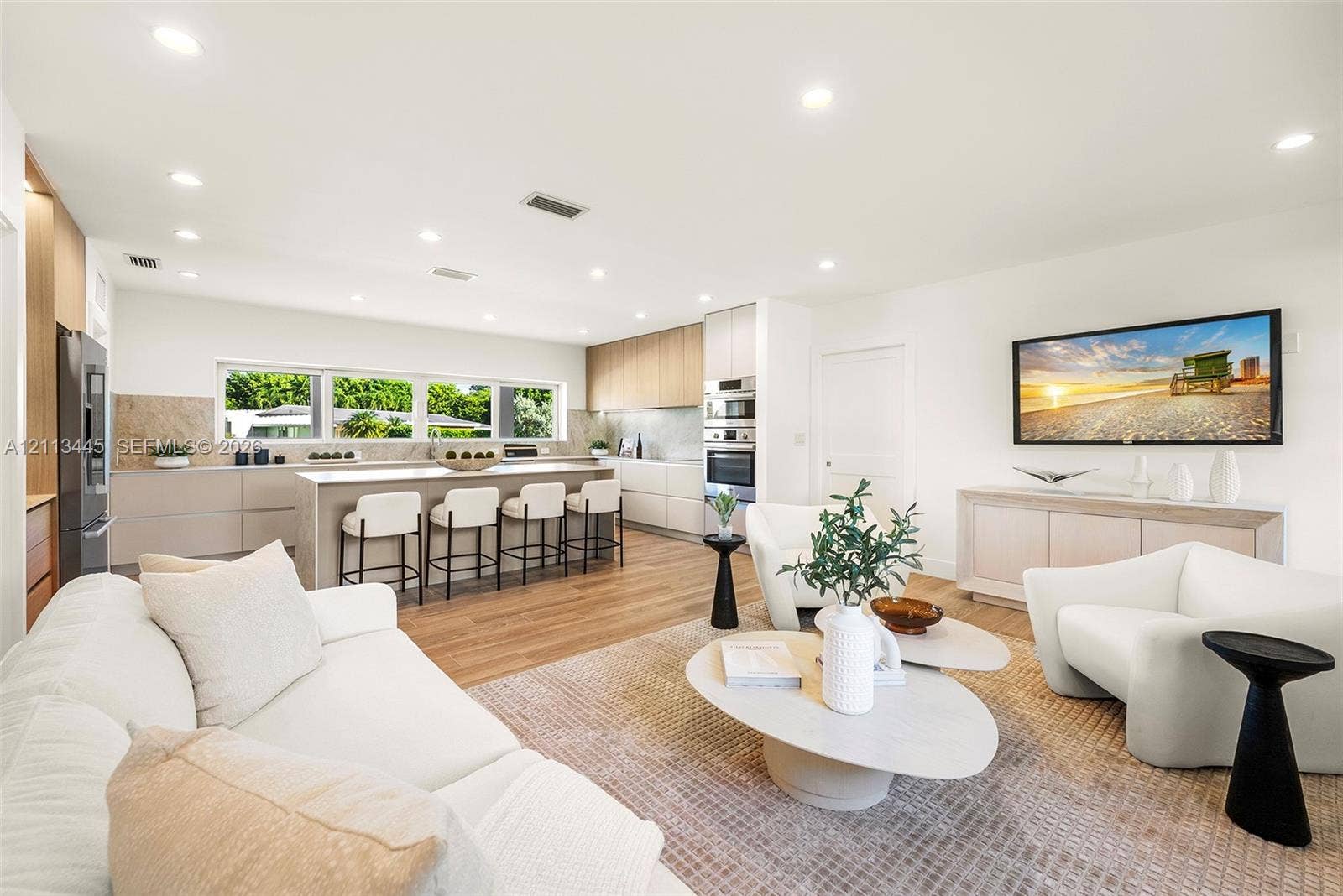 6951 SW 134th Street, Pinecrest, Pinecrest, FL 33156 Open-concept living space featuring wood-finish flooring, recessed lighting, a central island with stone-finish countertops, handleless cabinetry, and built-in stainless steel appliances