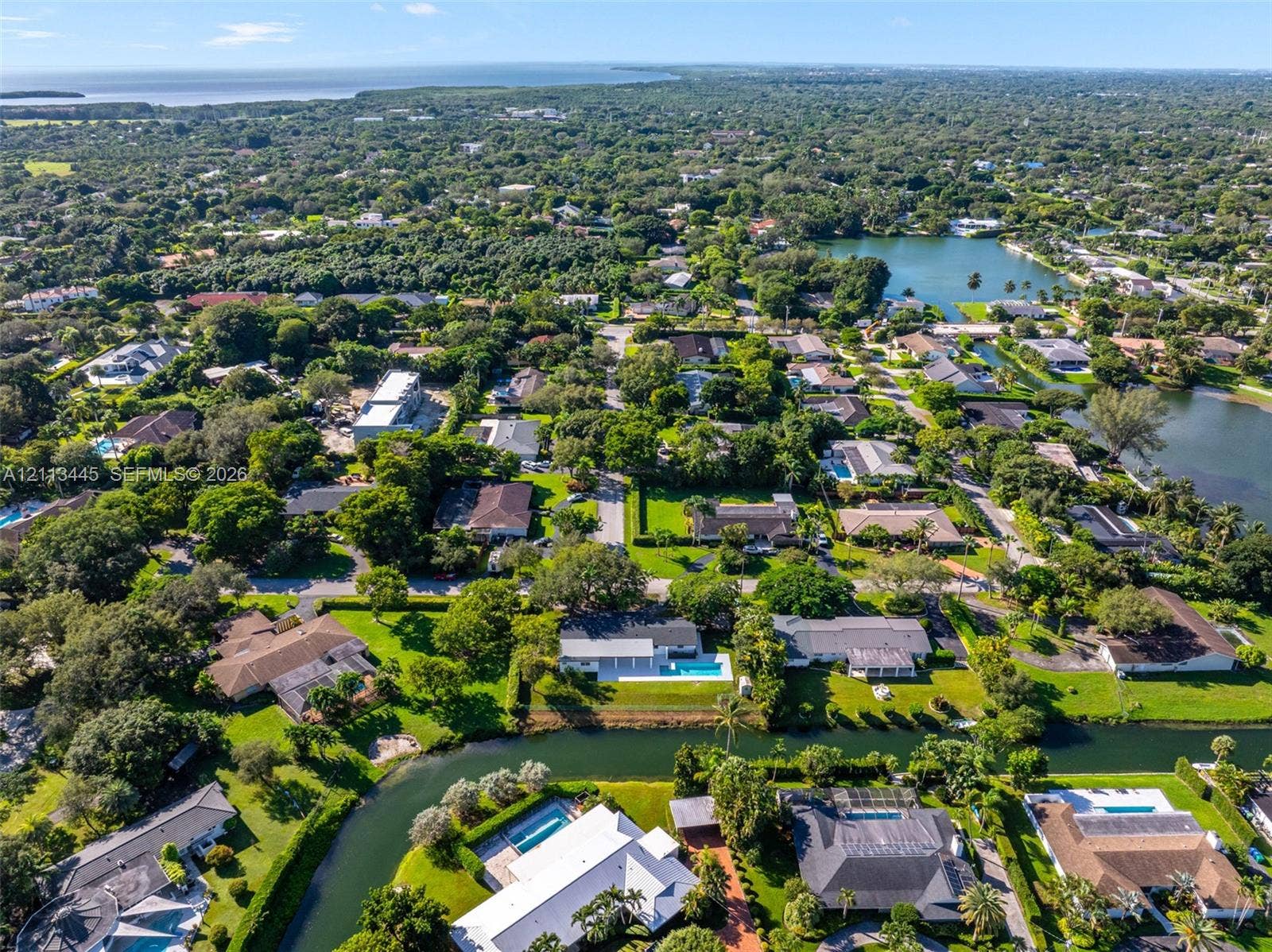 6951 SW 134th Street, Pinecrest, Pinecrest, FL 33156 Aerial perspective featuring waterfront residential properties, mature tree canopy, integrated canal systems, and proximity to the coastline