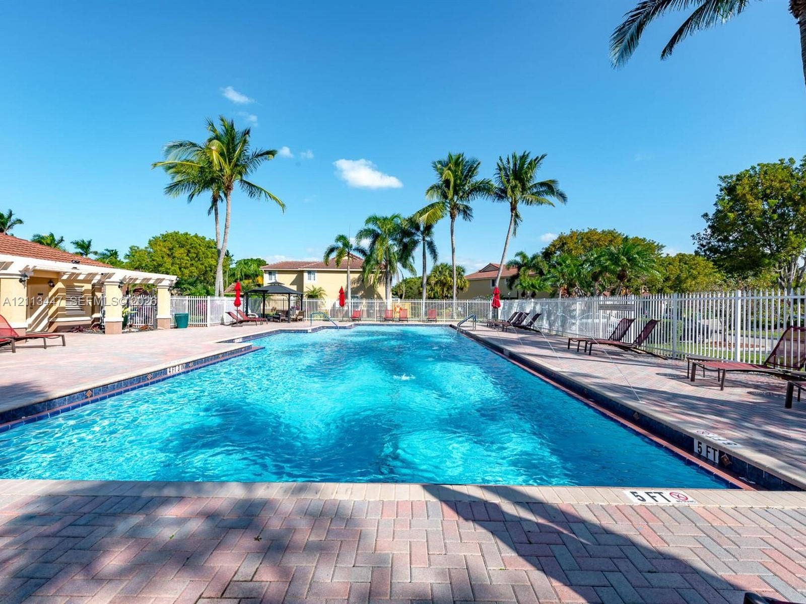 3818 San Simeon Circle, #3818, Weston, Weston, FL 33331 Rectangular swimming pool with brick paver decking, surrounded by white perimeter fencing and mature palm trees