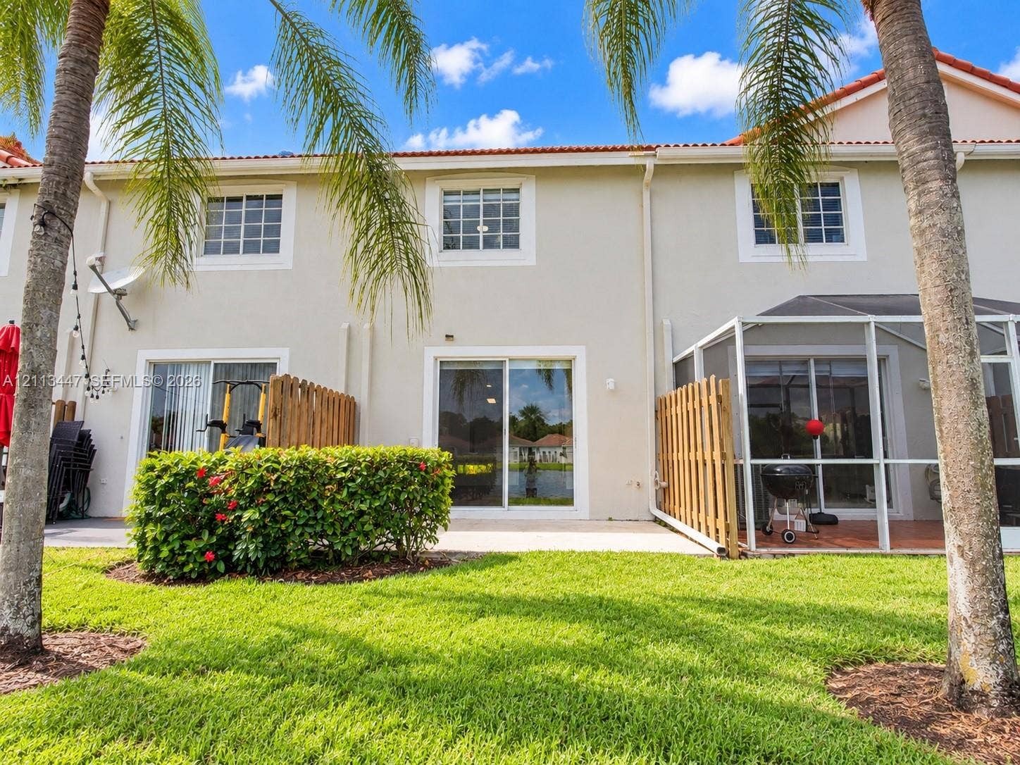 3818 San Simeon Circle, #3818, Weston, Weston, FL 33331 Stucco exterior featuring sliding glass doors, a screened-in patio, wooden privacy fencing, and a concrete slab